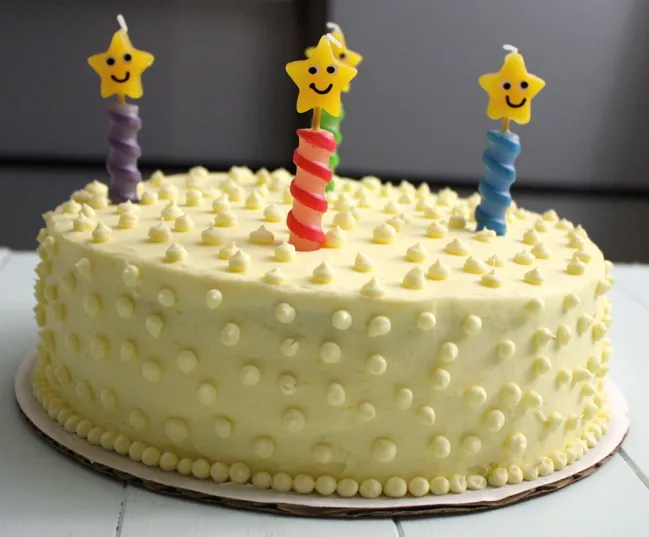 coconut mango cake with fresh strawberries, decorated with piped dots